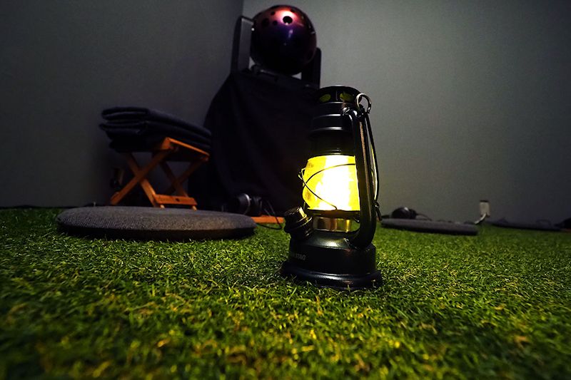 暗い部屋のなかに人工芝とランタン。芝生の上に座り、ヘッドホンで音楽を聴きながら楽しむプラネタリウムです。中央奥に見えるのが投影機